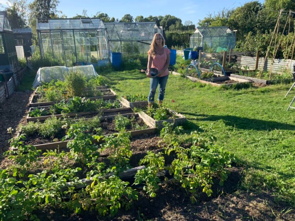 Photo showing Justine Alderney-Williams of The Wild Dyery with a bowl of fresh leaf indigo dye at her food, fibre and dye allotment.